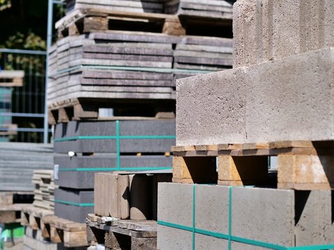 Heavy concrete blocks and stacked pallets with building supplies at an outdoor construction material storage yard.