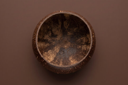 Top down view of an empty natural coconut shell bowl on a brown background