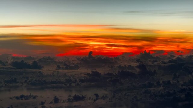 flying across and above cloudy ocean landscape with deep orange early morning sky in the background - 4k aerial video footage 