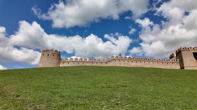 Ancient Stone Fortress Wall and Tower on Green Hill Under Blue Sky