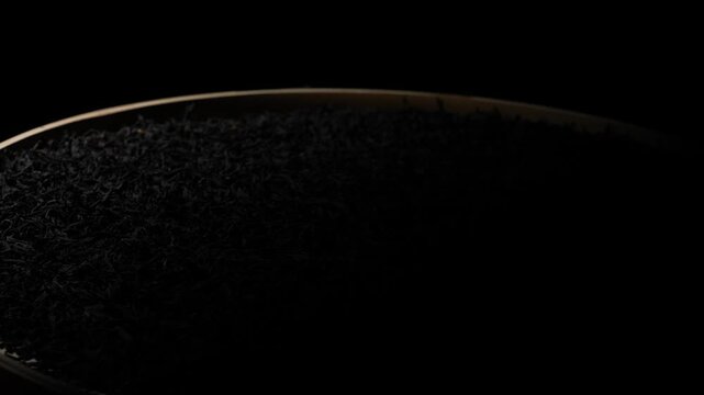 Close-Up of Dry Black Tea Leaves in a Bowl on Black Background