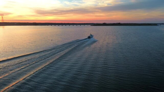 Peaceful jetski rider silhouette speeding across Lake Chairel at red purple sunset leaving water trail during drone pov aerial flight over protected nature reserve in Tampico Tamaulipas Mexico