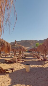 Desert beach scene with wooden loungers and straw umbrella Egypt. Hurghada.Siva Golden Bay Makadi