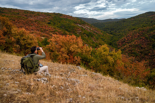 Hiker observing landscape in autumn near a valley in the mountains