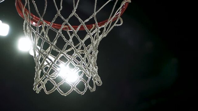 asketball player scoring a point as ball goes through hoop net in intense game action, Silhouette of basketball player jumping to dunk ball into hoop net on outdoor street court at sunset1