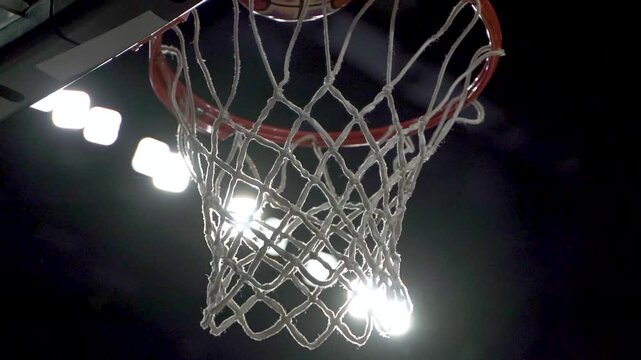 asketball player scoring a point as ball goes through hoop net in intense game action, Silhouette of basketball player jumping to dunk ball into hoop net on outdoor street court at sunset1