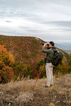Man taking photos of landscape in autumn hills with camera