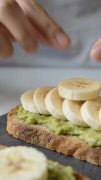 Vertical video: Picking slice, hands lining slices on avocado toast at home for neat row