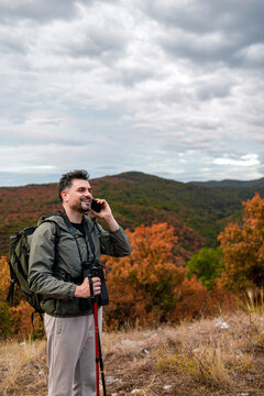 Man talking on phone while hiking in autumn landscape