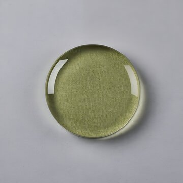 Green glass dome magnifier resting flat upon a light textured fabric surface inside studio photography