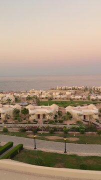 Coastal sunset resort view with white villas and lush gardens