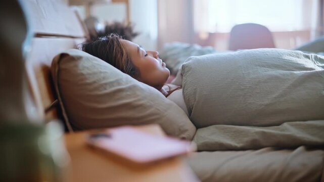 Woman waking up reaching phone bedside table. Multiracial couple morning bed.