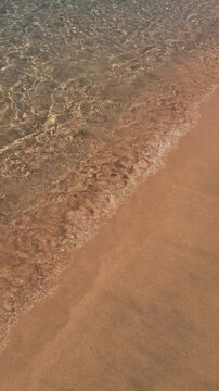 Tranquil beach waves gently lapping on golden sand shoreline