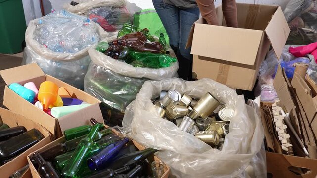 Waste recycling center, man sorting plastic, tin cans, cardboard boxes, textiles, shoes, glass bottles and electronic waste, environmental protection, sustainability
