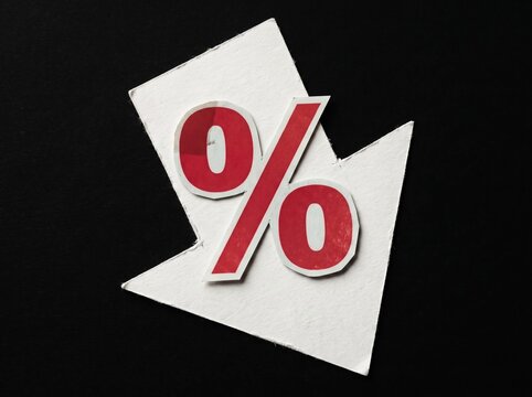 Red percent sign on white downward arrow representing decreasing interest rates or discounts