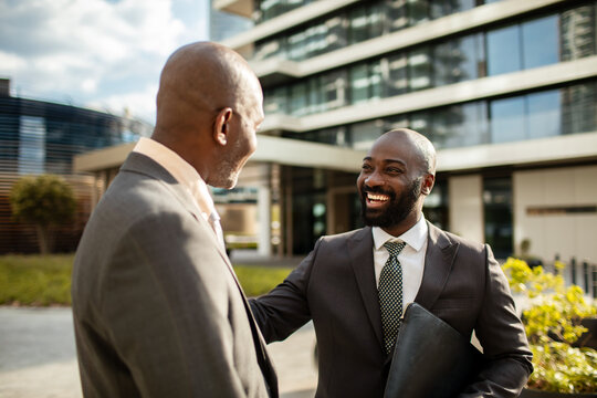 Smiling businessman greeting colleague outside office building