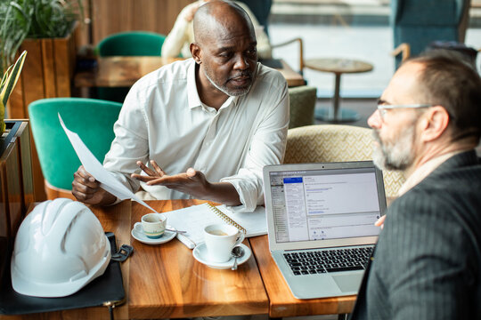 Two colleagues discussing construction project at cafe table