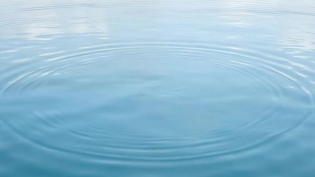 淡い青の水面に小さな波紋がゆっくり広がる、リラクゼーション、水をテーマにした広告、落ち着いた背景映像