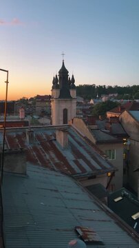 Panoramic top view of the historic Lviv cityscape at sunset with cozy rooftops and old brick buildings. Beautiful Armenian Cathedral tower stands out against the clear evening sky. 
