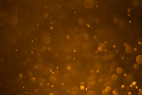 Abstract blurred background with golden bokeh lights on a dark background.