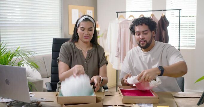 African American partners receiving orders, opening boxes, inspecting shirts, preparing shipments