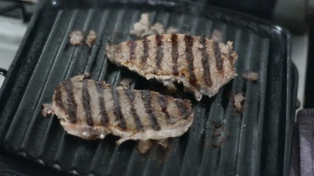 Two juicy beef steaks cooking on a grill pan with distinct grill marks
