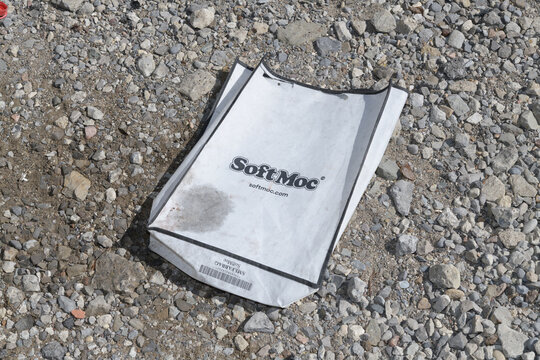 grungy, discarded bag with SoftMoc logo on a gravel ground in Toronto