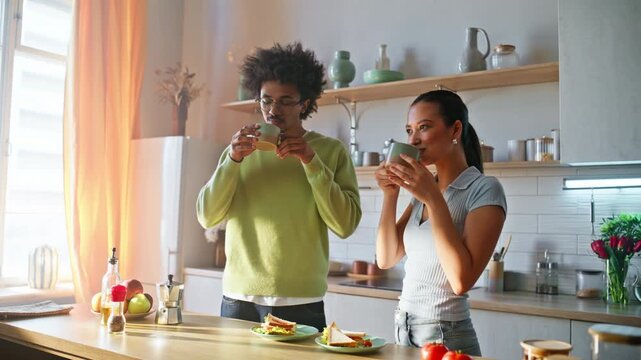 Couple drinking coffee cozy home kitchen. Man woman chatting laughing breakfast.