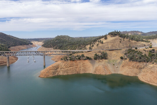 Lake Oroville with severely low water levels, boats clustered near West Branch Feather River Bridge and exposed cracked reservoir banks revealing drought-stricken California landscape