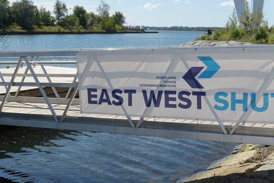 view of banner on side of pedestrian bridge at East-West Shuttle: Ookwemin Minising Stop, a transportation service, located here at 242 Cherry St, Toronto