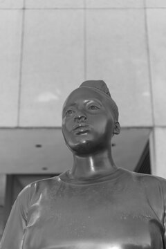 frontal, black and white view of Thomas J Price's "Moments Contained" a bronze figure depicting a young Black woman, installed outside the Art Gallery of Ontario, Toronto