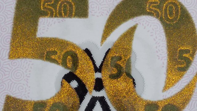 Close up of Mexican 50 peso banknote showing large gold number details and security patterns. Intricate printing and textured elements create a distinctive currency closeup.