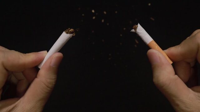 Hands breaking a cigarette in half to quit smoking