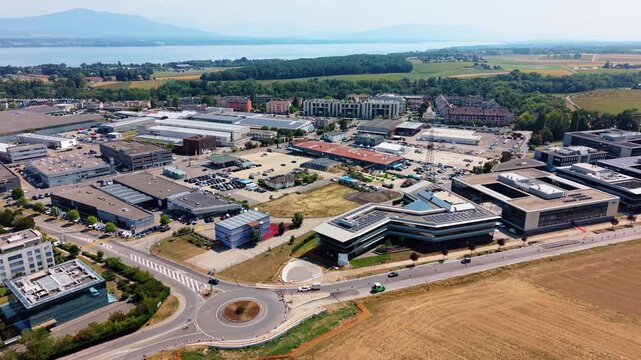 A roundabout and field border a business park near Nyon Switzerland, drone pulling back and rising