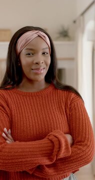 Vertical video: Adult African woman blinking at cam, smiling laughing folding arms at home headband