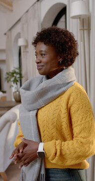 Vertical video: African woman hearing offscreen cue smiling and laughing posing at home with scarf