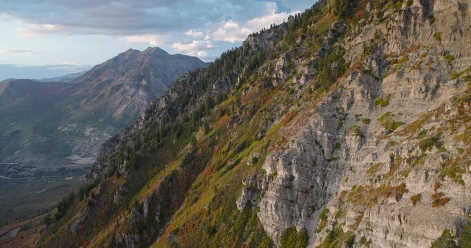 Grass and Autumn Trees On Side Of Majestic Utah Rocky Mountains At Sunset - Aerial Shot