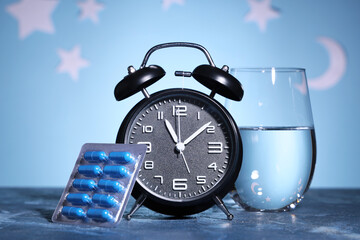 Naklejka na ściany i meble Insomnia and sleep disorder treatment, blue medication capsules with alarm clock and water glass for nighttime health routine and medical therapy