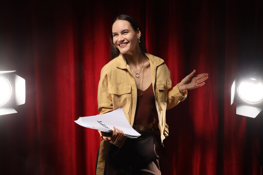 Audition and casting call, young actress holding script on stage with spotlight and red curtain background for theater performance and entertainment industry