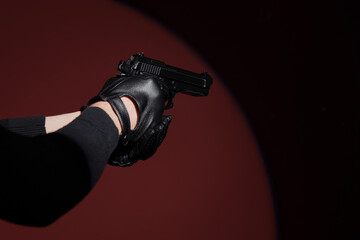 Obraz premium Crime and violence prevention, person in black leather gloves holding a handgun in a dark room with dramatic spotlight for thriller movie production