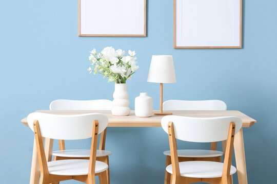 Interior design and home staging, dining room with wooden table and chairs against blue wall with empty picture frames for modern living space decor
