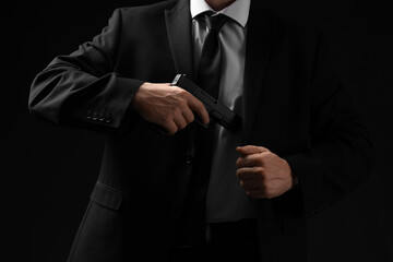 Obraz premium Security and executive protection, bodyguard in suit drawing a handgun for defense and law enforcement operations in a dark professional environment