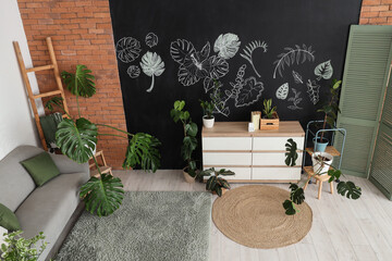 Fototapeta premium Biophilic interior design and home decor, modern living room with monstera plants and botanical chalk wall art in a cozy apartment with brick wall