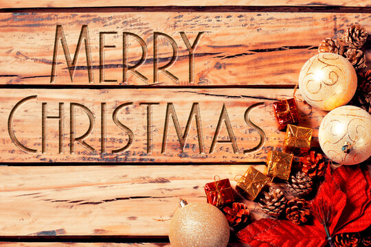 Merry Christmas text in an elegant font carved into rustic wood, featuring Christmas decorations.