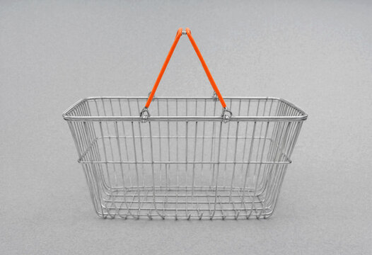 Empty wire shopping basket with orange handle against neutral background