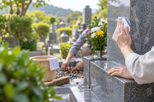 年忌法要前に先祖のお墓を掃除する家族