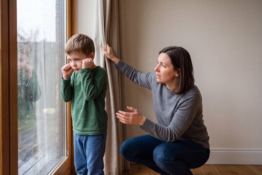 Autism Comforting a Child: A mother gently comforts her sad son who is looking out the window, offering solace and support during a moment of distress.