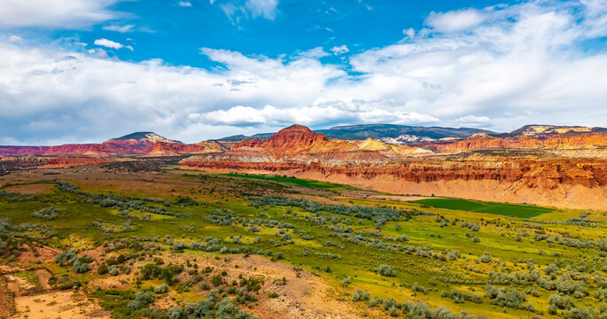 Red sandstone cliffs border lush green valley near Capitol Reef