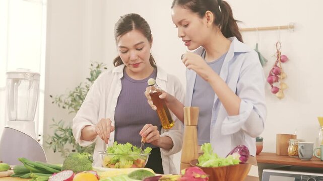 Happy young lesbian couple preparing a healthy fresh vegetable salad together in the modern kitchen.
