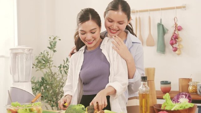 Happy young lesbian couple preparing a healthy fresh vegetable salad together in the modern kitchen.